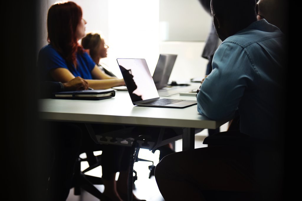 people at a desk with laptops
